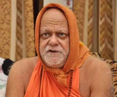 Close portrait of Nishchalananda Saraswati, his head covered by a saffron cloth, gazing thoughtfully